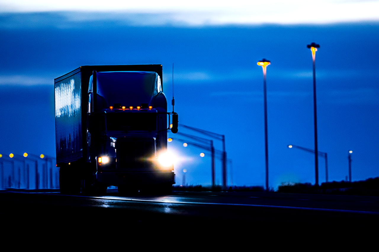 A transport truck driving down the road at dusk